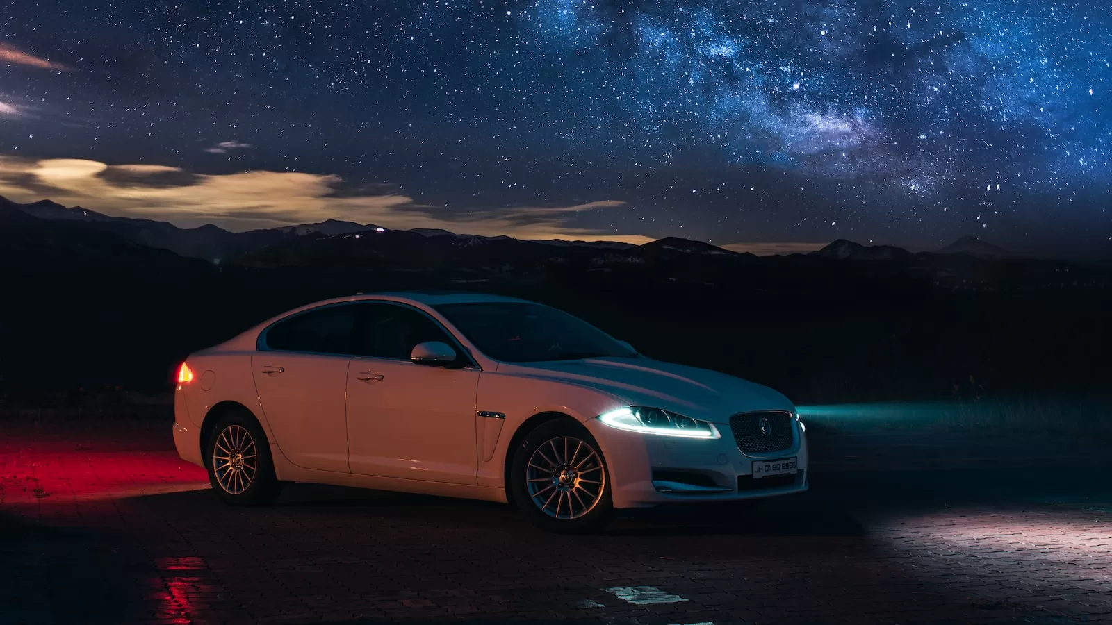 a white car parked in front of a night sky filled with stars